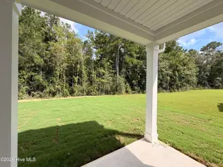 8611 Blue Haw Way Lot 124, Leland, NC 28451 — 5-bedroom home in Indigo Preserve, Leland, NC, photo 6 of 33: Backyard space with covered porch
